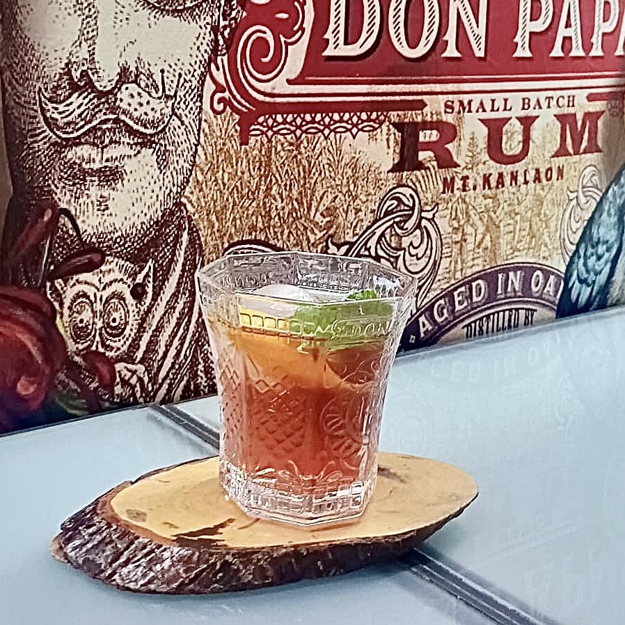 COCTEL artesanal con Ron don Papa en vaso labrado y posavasos de madera orgánico.